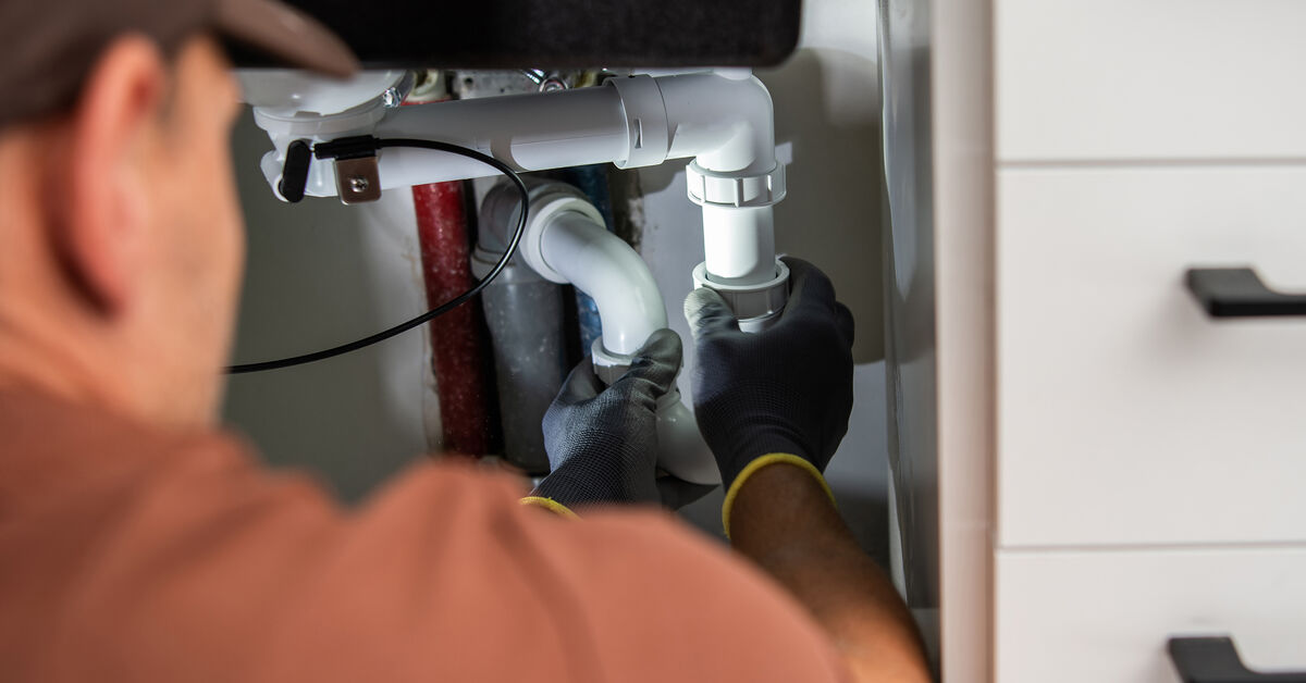 Plumber checking plumbing under sink